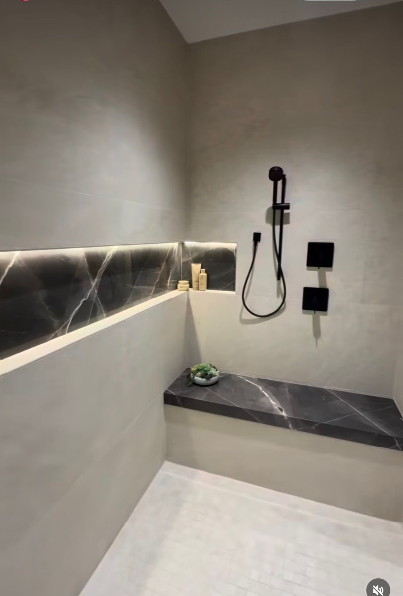 Graue Dusche mit Marmor-Sitzbank und schwarzen Armaturen